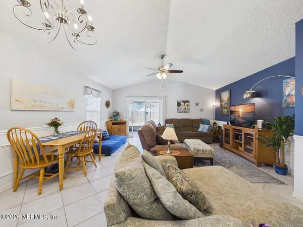 a living room with furniture kitchen view and a chandelier