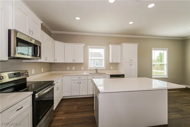 a kitchen with a sink a stove top oven and white cabinets