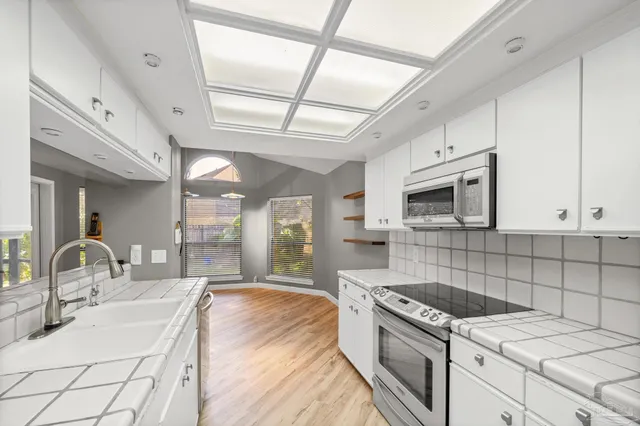 a kitchen with granite countertop a sink stainless steel appliances and white cabinets