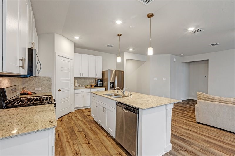 2643 Homestead Rnch Lane Crosby, TX 77532 - Photo 15 of 23 a kitchen with a stove a sink a refrigerator and white cabinets with wooden floor