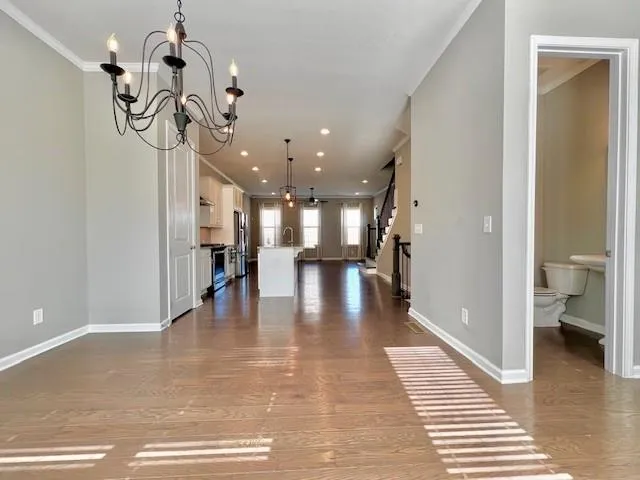 a view of a hallway with wooden floor and a living room