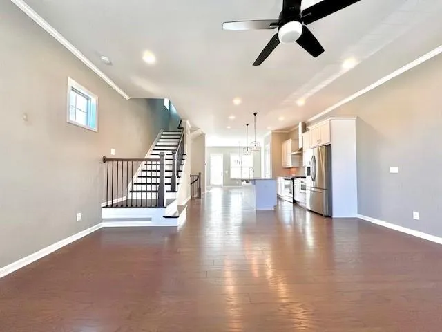 a view of an empty room with wooden floor and windows