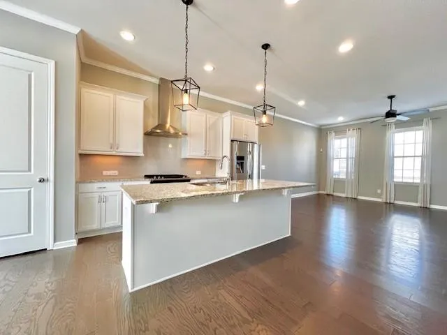 a open kitchen with stainless steel appliances granite countertop a stove a sink dishwasher a refrigerator and a wooden floor