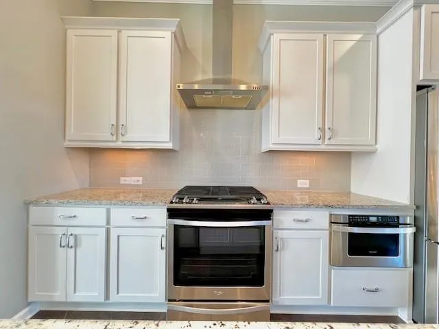 a kitchen with granite countertop white cabinets and stainless steel appliances
