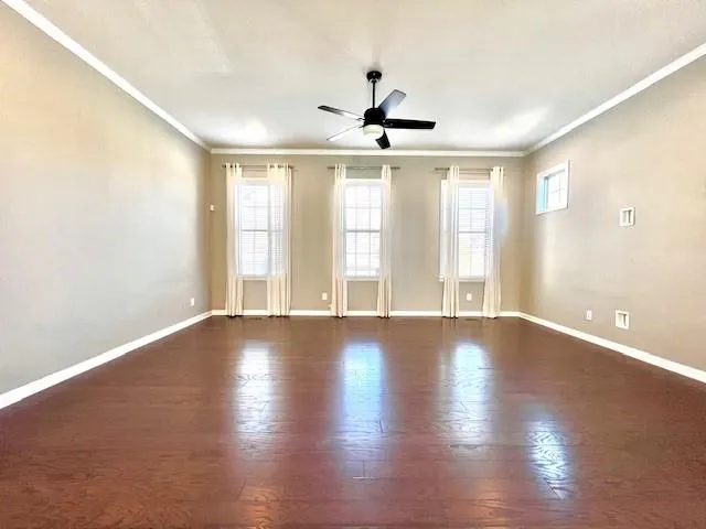 a view of an empty room with window and wooden floor
