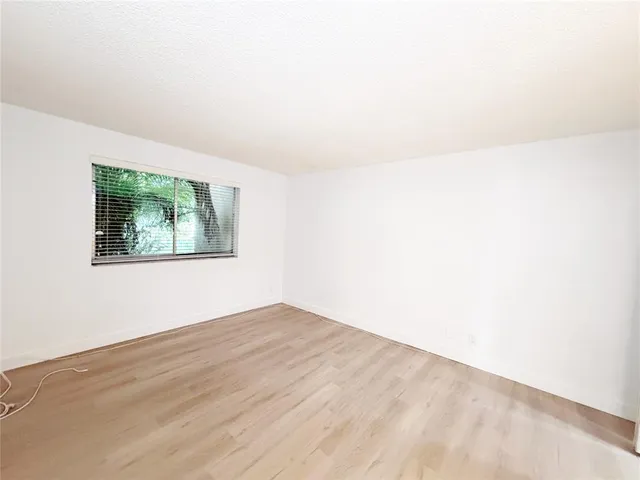 a view of an empty room with wooden floor and window