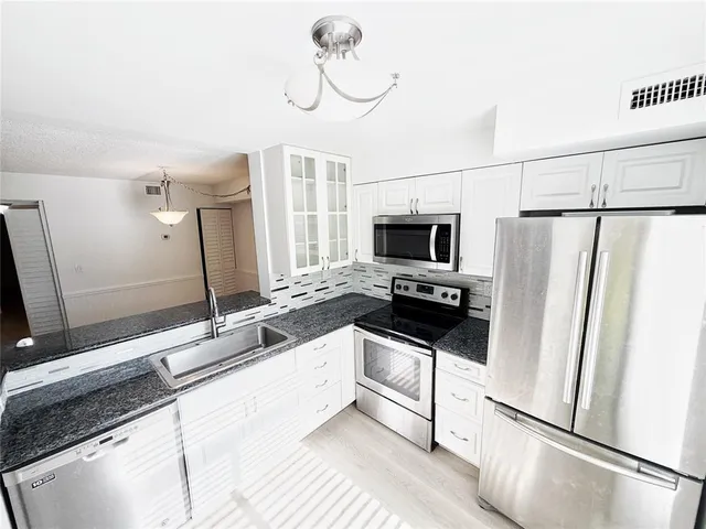 a kitchen with stainless steel appliances a refrigerator sink and microwave