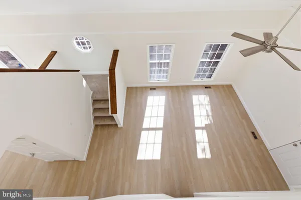 a view of an empty room with wooden floor and windows