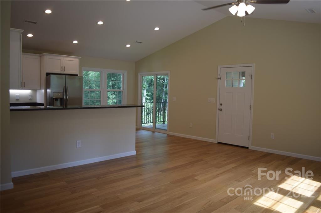 162 Gold Run Rutherfordton, NC 28139 - Photo 5 of 26 an empty room with wooden floor kitchen view and windows