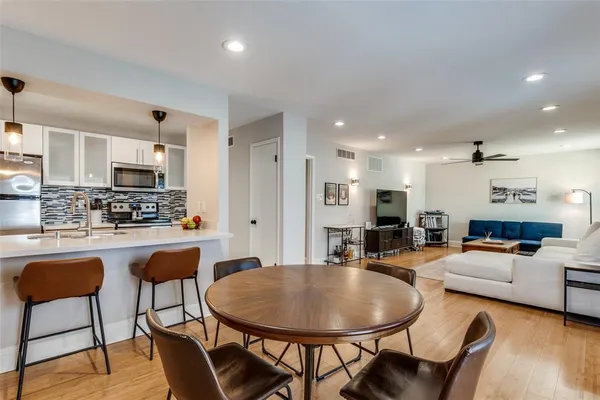 a kitchen with stainless steel appliances kitchen island granite countertop a dining table chairs and a refrigerator