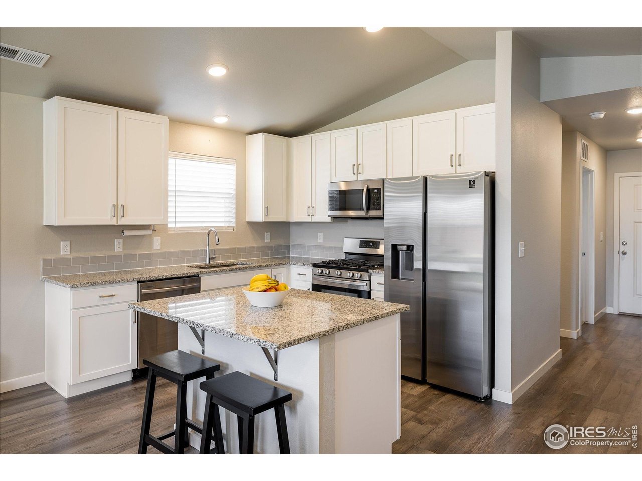 735 South Hoover Avenue Fort Lupton, CO 80621 - Photo 6 of 21 a kitchen with kitchen island a refrigerator stove microwave and cabinets