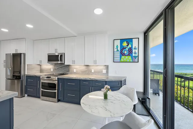 a kitchen with stainless steel appliances granite countertop a stove top oven a sink dishwasher a dining table and chairs with wooden floor