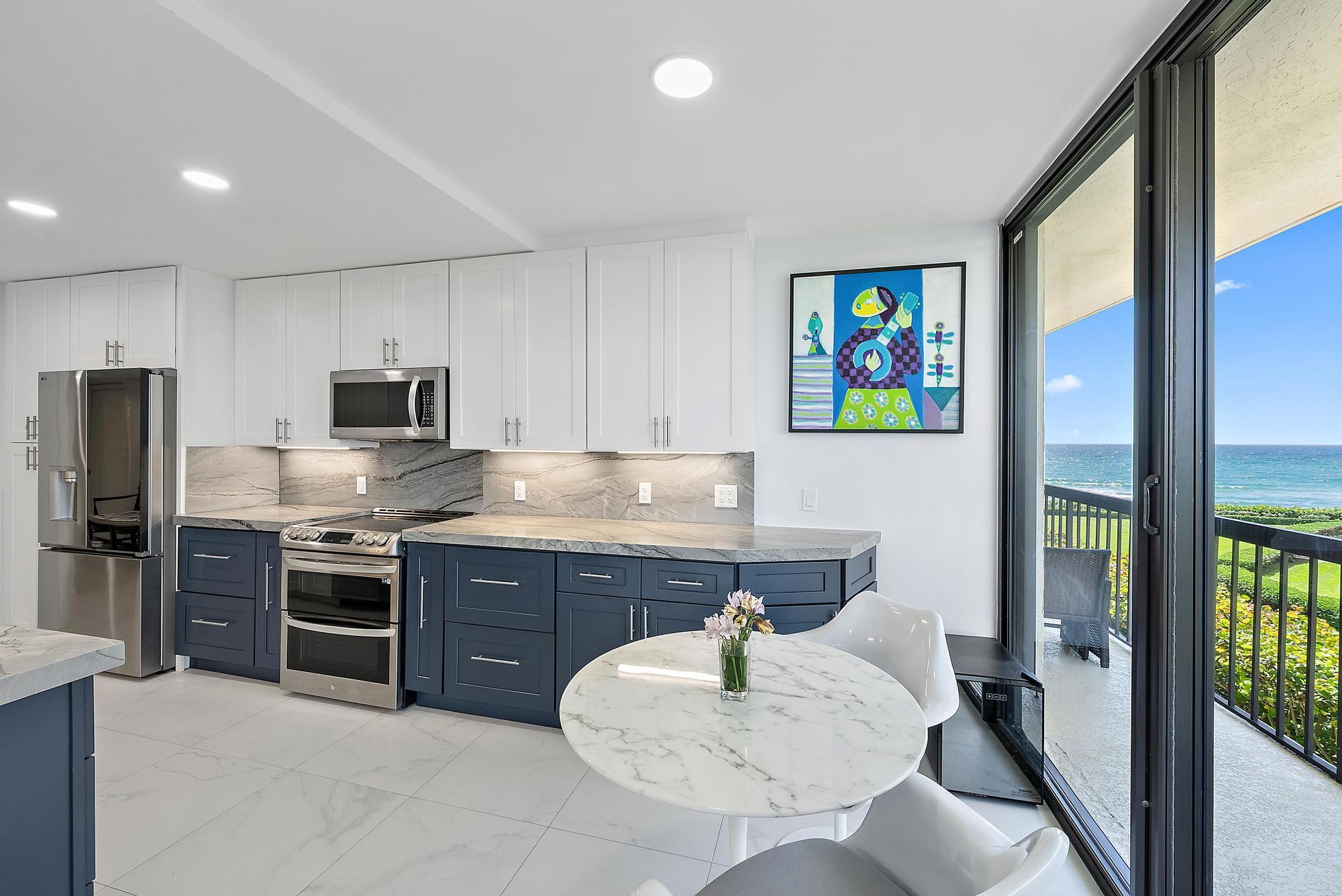 3390 South Ocean Boulevard, Unit 301 Palm Beach, FL 33480 - Photo 14 of 46 a kitchen with stainless steel appliances granite countertop a stove top oven a sink dishwasher a dining table and chairs with wooden floor