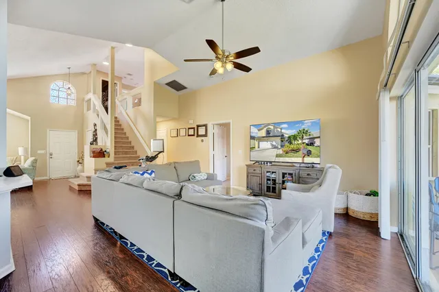 a living room with couches and kitchen view with wooden floor