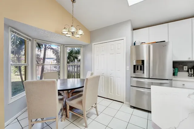 a kitchen with stainless steel appliances granite countertop a refrigerator a stove a dining table and chairs with wooden floor