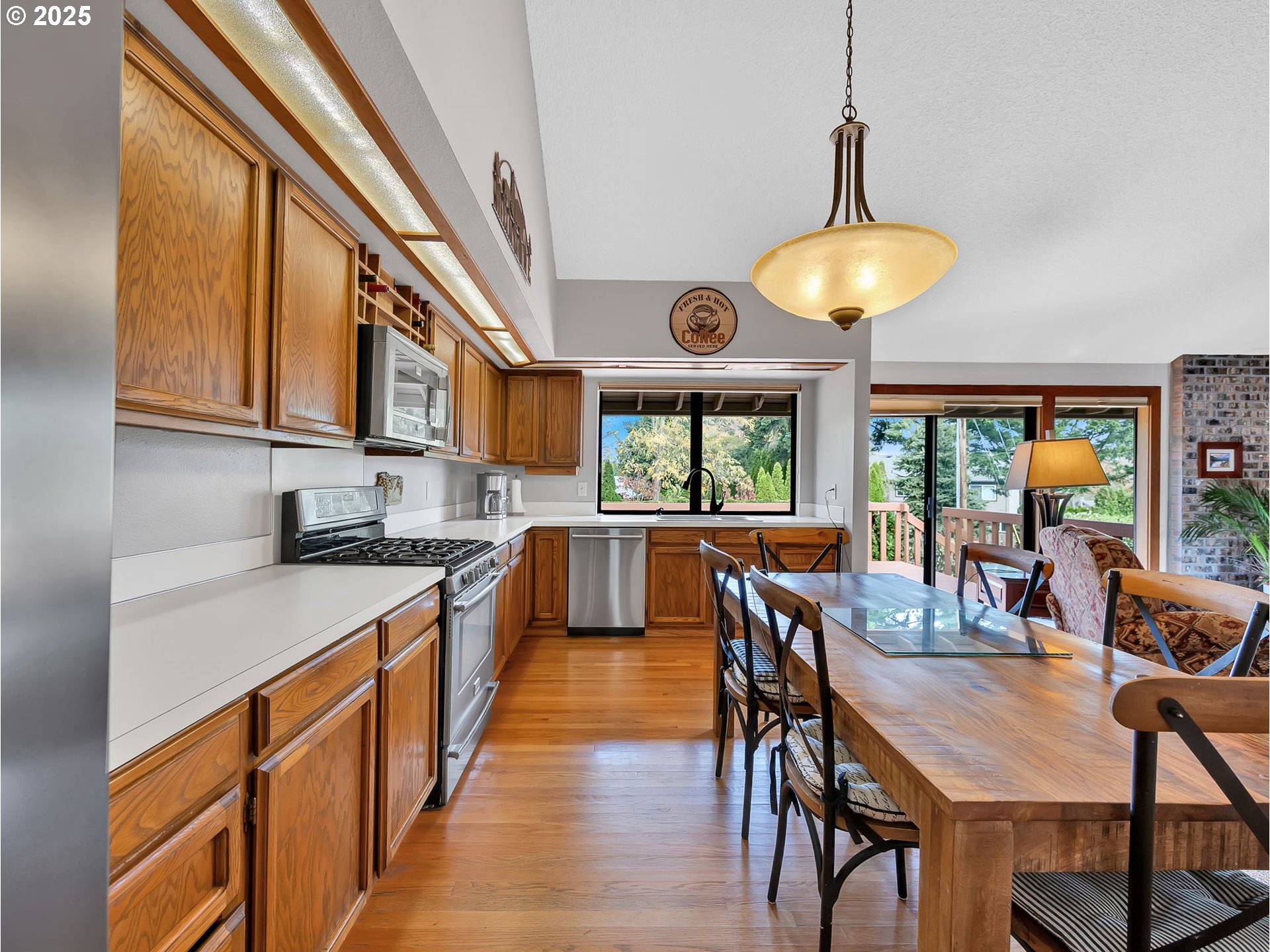 3239 Southwest 26th Street Gresham, OR 97080 - Photo 9 of 47 a kitchen with stainless steel appliances granite countertop a stove a refrigerator a kitchen island a dining table and chairs with wooden floor
