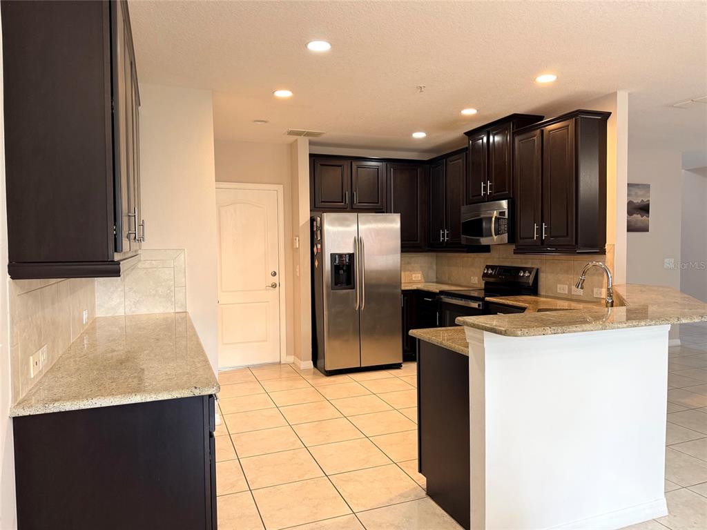2084 Water Tupelo Way Ocoee, FL 34761 - Photo 4 of 34 a kitchen with stainless steel appliances a refrigerator sink stove microwave and cabinets