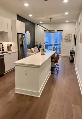 a large white kitchen with a sink a refrigerator and chairs
