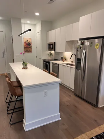 a kitchen with a sink a refrigerator and white cabinets