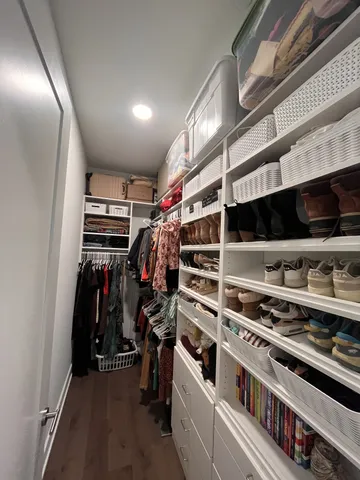 a view of walk in closet with clothes and shoes