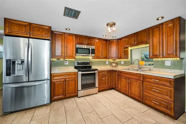 a kitchen with stainless steel appliances granite countertop a stove top oven a sink dishwasher a dining table and chairs with wooden floor