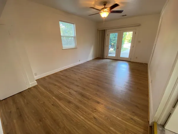 a view of an empty room with wooden floor and a window