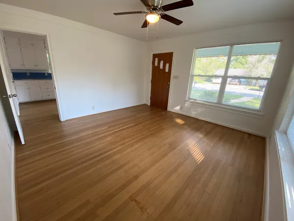 a view of an empty room with wooden floor and a window