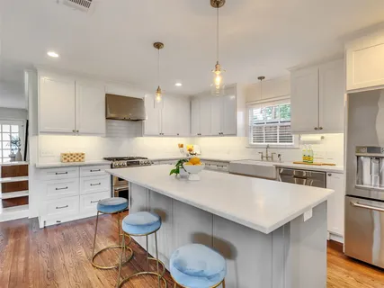 a kitchen with stainless steel appliances a table chairs microwave and cabinets