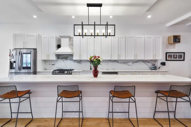 a kitchen with stainless steel appliances granite countertop a stove a sink and a refrigerator with white cabinets