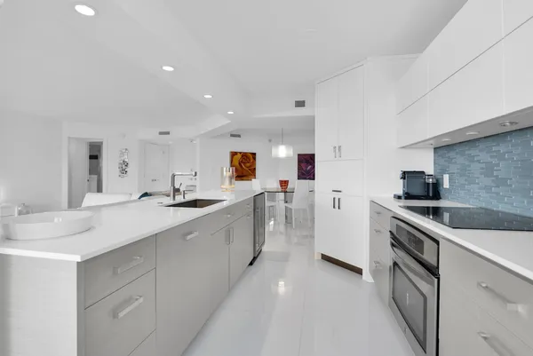 a large white kitchen with stainless steel appliances granite countertop a lot of counter space and wooden floors