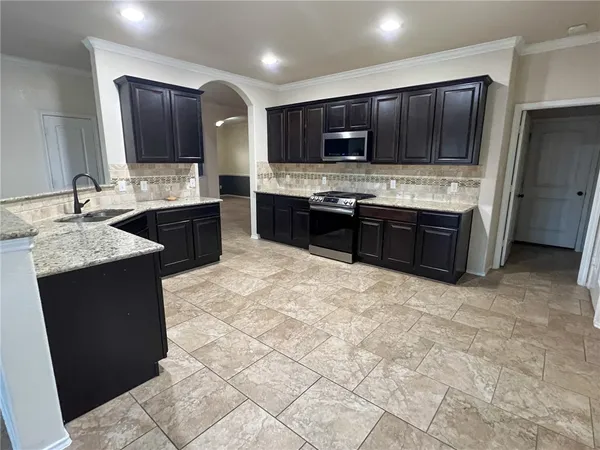 a large kitchen with granite countertop a stove microwave and refrigerator