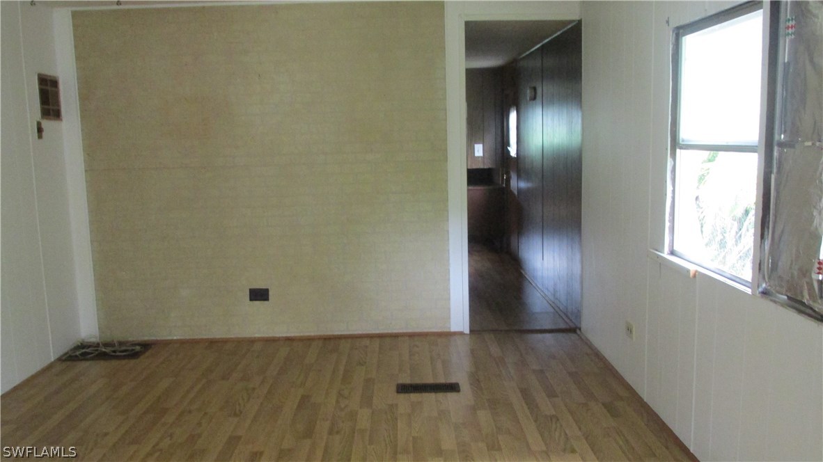 7301 Pinehurst Road Bokeelia, FL 33922 - Photo 6 of 11 an empty room with wooden floor and windows
