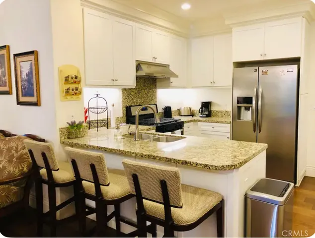 a kitchen with stainless steel appliances granite countertop a table chairs and a refrigerator