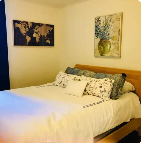 a bedroom with a bed and painting on the wall