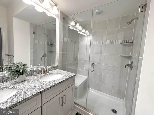 a bathroom with a granite countertop shower sink and mirror
