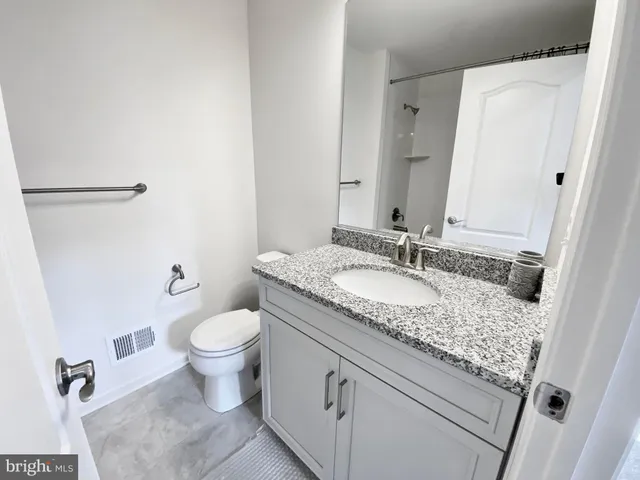 a bathroom with a granite countertop sink a toilet and a mirror