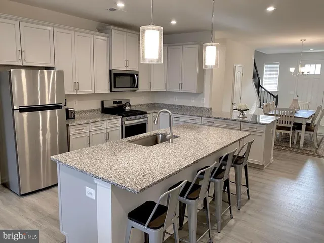 a kitchen with stainless steel appliances granite countertop a kitchen island hardwood floor and a sink