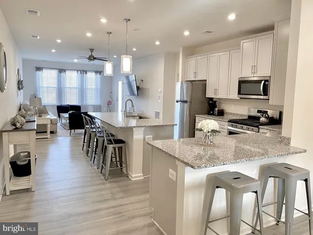 a kitchen with stainless steel appliances granite countertop a stove top oven a sink a dining table and chairs