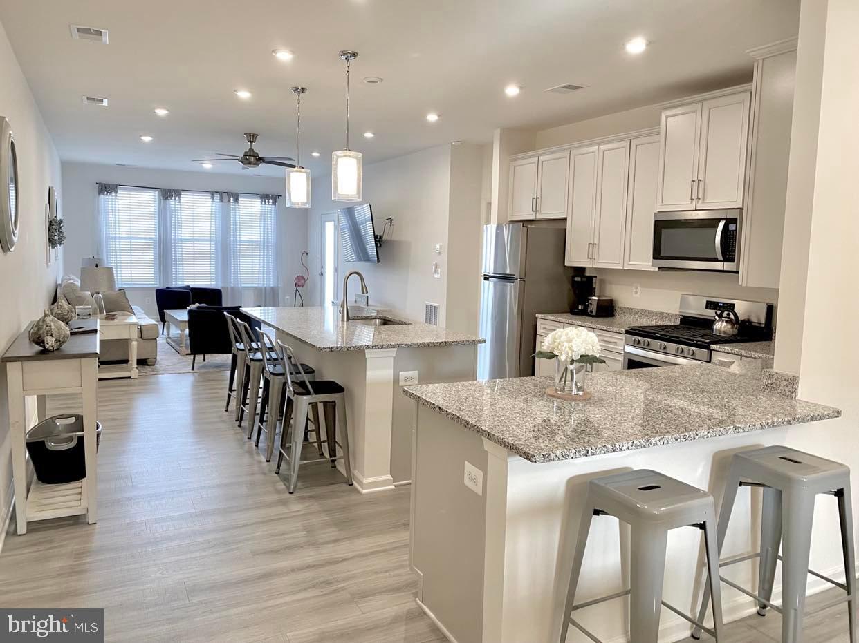 38035 Cross Gate Road Millville, DE 19967 - Photo 4 of 22 a kitchen with stainless steel appliances granite countertop a stove top oven a sink a dining table and chairs