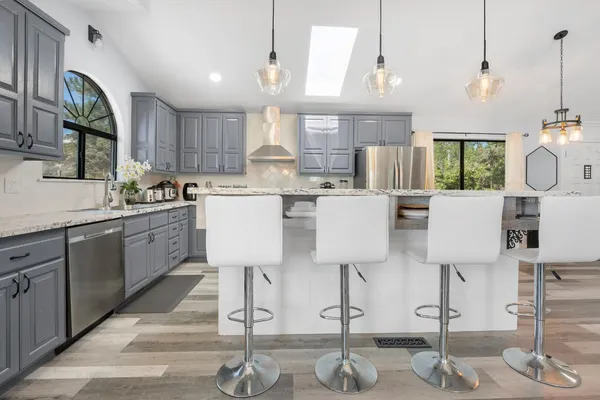 a kitchen with stainless steel appliances kitchen island granite countertop a table chairs in it and white cabinets