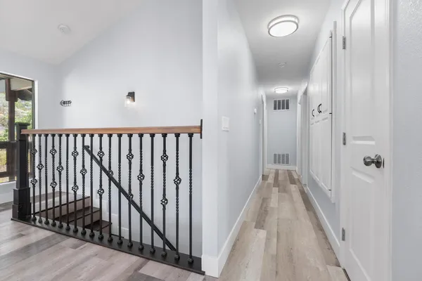 a view of a hallway with wooden floor and a bathroom