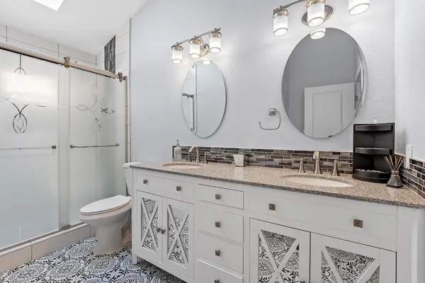 a bathroom with a double vanity sink mirror and toilet
