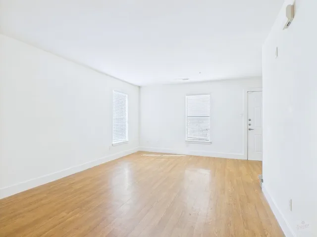 a view of a big room with wooden floor and windows