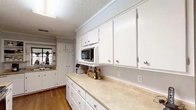 a kitchen with stainless steel appliances granite countertop a sink a stove and white cabinets with wooden floor