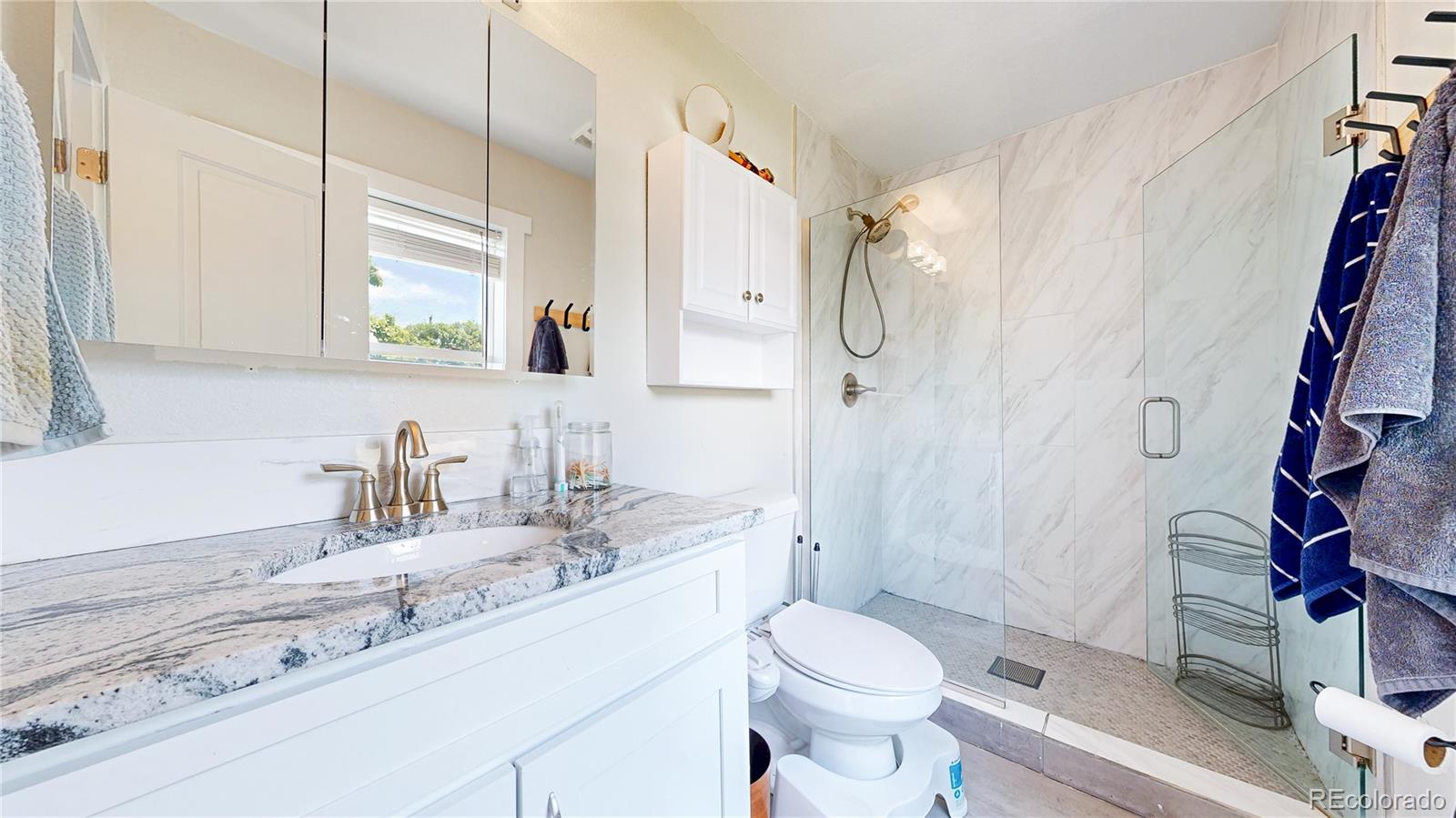 1741 West 55th Place Denver, CO 80221 - Photo 15 of 36 a bathroom with a granite countertop sink mirror vanity and toilet