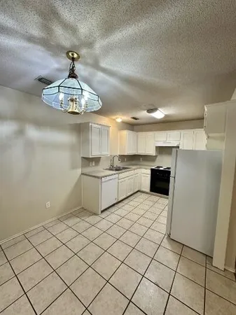 a kitchen with stainless steel appliances a sink a stove a refrigerator cabinets and chairs
