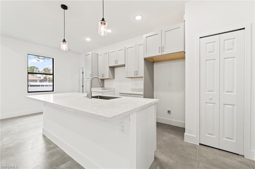 3705 37th Street Southwest Lehigh Acres, FL 33976 - Photo 13 of 35 a kitchen with kitchen island white cabinets and white appliances