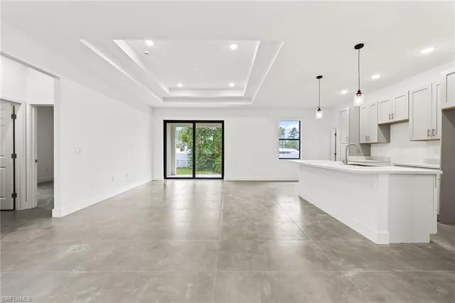 a view of an empty room with kitchen and window