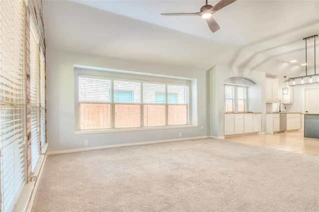 an empty room with windows and ceiling fan