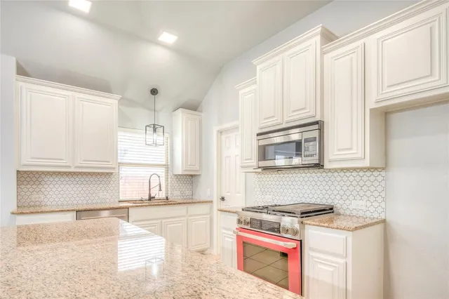 a kitchen with stainless steel appliances granite countertop a stove a sink and white cabinets
